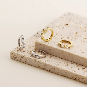 Detailed close-up of marquise zircon earrings in gold and silver finish on stone