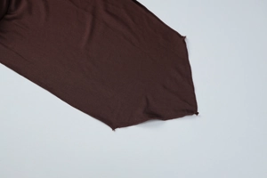 Gros plan de l'ourlet d'une robe en maille marron foncé avec couture de finition précise