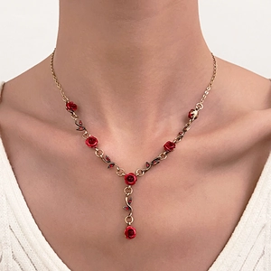 Détail d'un collier vintage doré avec roses rouges et cristaux, porté par un mannequin