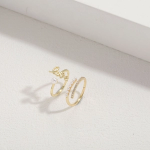 Gold-plated Love ring set with pearls and zircon crystals on a minimalist background