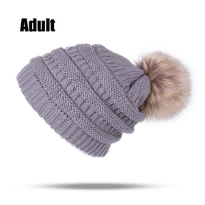 Close-up of grey knit adult winter hat with a soft faux fur pom-pom and thick ribbed texture