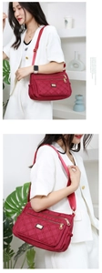 Close-up of red quilted nylon crossbody bag featuring multiple zippers and adjustable strap