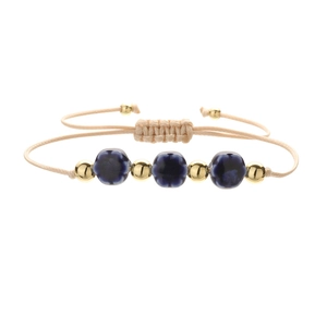 Close-up of adjustable woven cord bracelet with blue ceramic flowers and gold beads
