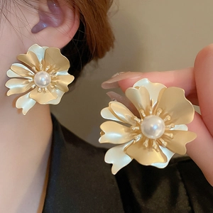 Detail of matte gold flower earring with white pearl center and model display