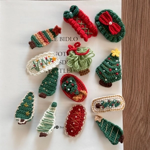 Detail of handmade crochet Christmas hair clips with trees and bows on white book
