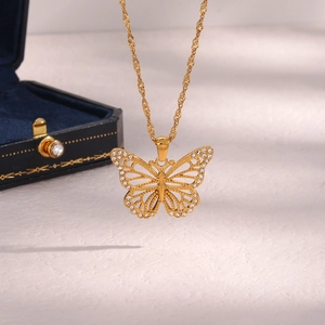 Macro shot of gold hollow butterfly pendant with sparkling white zircons and twist chain