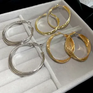 Trois paires de créoles torsadées en or 18 carats et argent dans un écrin de bijoux gris luxe