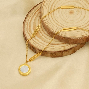Detail of gold necklace with circular white shell pendant on wooden coasters
