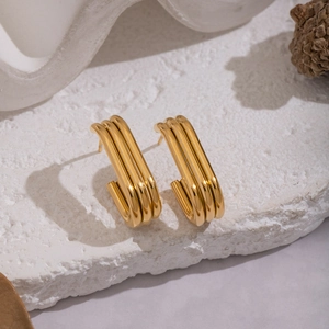 Minimalist geometric 18K gold plated C-shaped earrings displayed on a white stone background