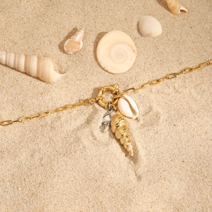 18K gold titanium steel necklace with seashell and silver crab charms on sandy beach