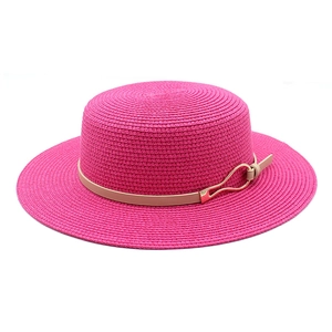 Macro detail of rose red woven straw hat with beige leather strap and gold metal buckle