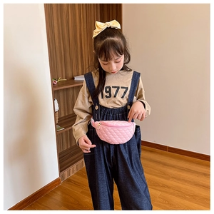 Pink quilted crossbody waist bag for children worn by a young model in a cozy setting
