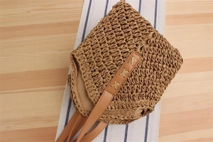 Detailed close-up of khaki straw woven texture and brown PU leather strap with stitching