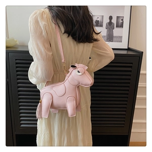 Detail of pink pony shaped crossbody bag with gold hardware and tassel decoration