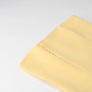 Gros plan sur la texture du tissu plissé jaune montrant les détails d'un matériau élégant