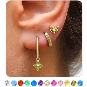 Detail of gold cartilage hoop earrings set with colorful birthstones shown on ear