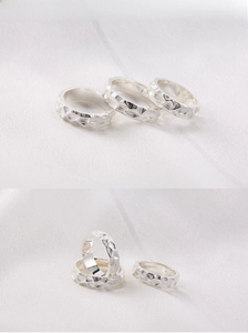 Detail of silver hammered texture on men's stainless steel rings over white fabric