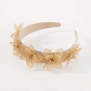 Détail de fleurs en résine ambre avec étamines dorées sur un serre-tête beige
