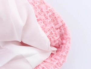 Detailaufnahme der rosa Tweed-Struktur und des weißen Innenfutters dieser Jacke
