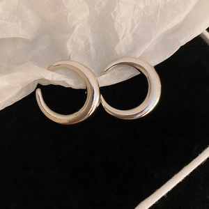 Macro view of polished silver geometric C-shaped earrings on dark background
