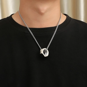 Close-up of a silver industrial nut pendant necklace worn on a black sweater background
