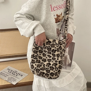 Detail of soft leopard print faux fur shoulder bag held by a model in casual setting