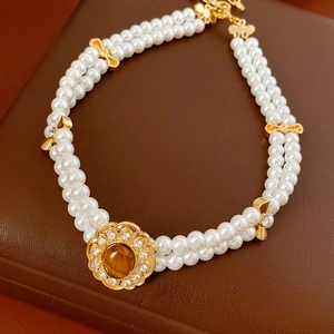 Dettaglio ravvicinato della collana di perle vintage a due fili con ciondolo occhio di tigre