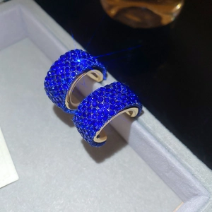 Close-up of royal blue crystal C-shaped earrings with gold plating and rhinestones