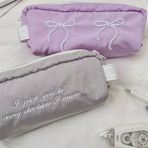 Detail of embroidered bow on purple nylon pencil case with high-capacity zipper design
