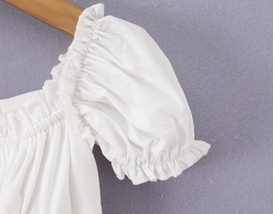 Détail des manches bouffantes élastiques et texture du coton sur le haut blanc
