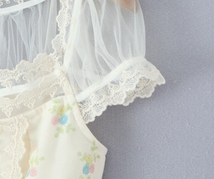 Détail des bords en dentelle délicate et des manches en mesh à imprimé floral