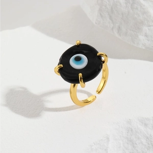 Detailed view of adjustable gold evil eye ring with black resin inlay and blue glass pupil