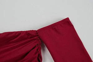 Detail of burgundy dress shoulder featuring elegant ruched fabric and precise stitching