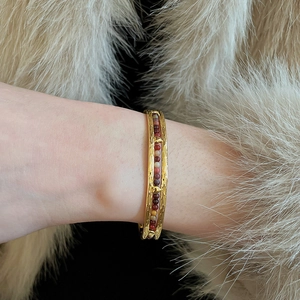 Détail d'un bracelet vintage doré avec des perles de pierre colorées sur de la fausse fourrure