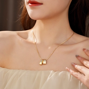 Close-up of golden brushed cylinder pendant with zircon stone on elegant neck chain
