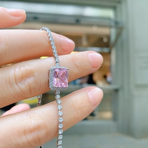 Close-up of a silver bracelet featuring a central pink rectangular gem with small diamonds