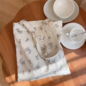 Détail d'un sac en coton fleuri avec écusson 'Animal patterns' sur table en bois