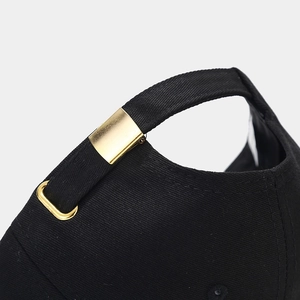 Detail of black cotton baseball cap showing adjustable gold metal buckle and strap back