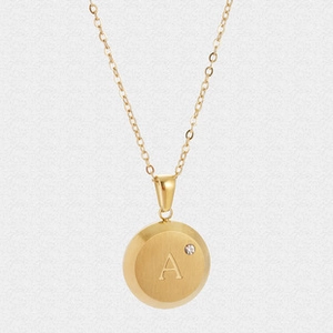 Detailed macro of golden letter A pendant with shell texture and a small diamond