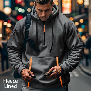 Detail of grey fleece hooded sweatshirt featuring orange zipper and utility sleeve pocket