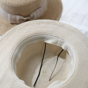Detail of adjustable inner drawstring and sweatband inside the woven straw boater hat