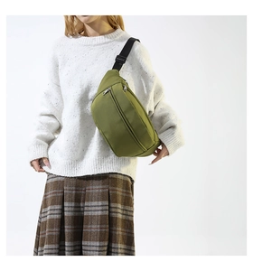 Dettaglio di una borsa da petto verde oliva minimalista indossata a tracolla casual