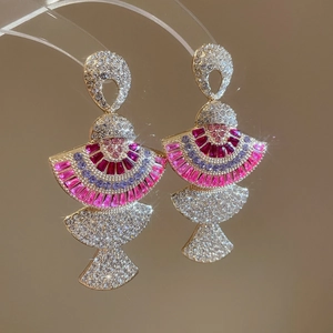 Close-up of fan-shaped crystal earrings with pink and purple gems in gold plating