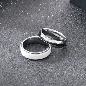 Anelli minimalisti in ceramica bianca e acciaio al tungsteno grigio su fondo opaco