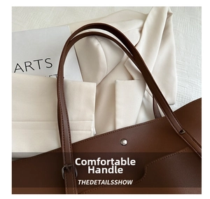 Detail of dark brown tote bag featuring adjustable wide shoulder strap and silver buckles