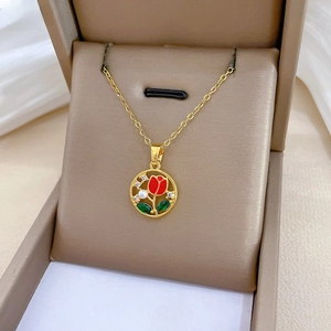Detail of gold tulip pendant with red enamel, green stones and pearl in a jewelry box
