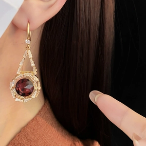 Detail of round red crystal drop earrings with sparkling zircon halo on gold hook