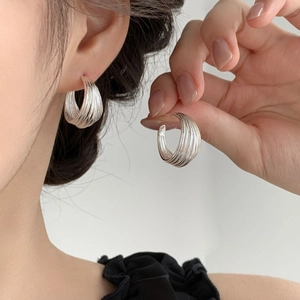 Detail showing the layered brushed texture and silver finish of the C-shaped hoop earrings