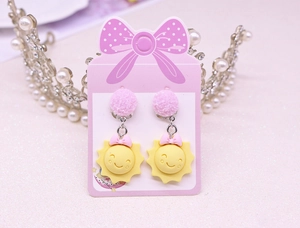 Close-up of cute yellow sun clip-on earrings with pink bows for girls on display card