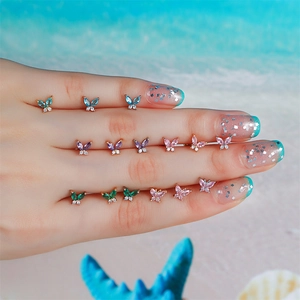 Detailed butterfly ear studs with marquise-cut colorful zircons held on a finger